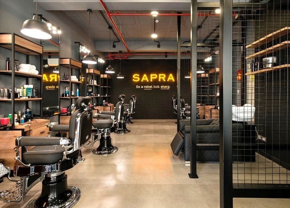 Interior moderno de Sapra Barbershop en Miraflores, Provincia De Lima, PE, mostrando sillas de barbero elegantes.