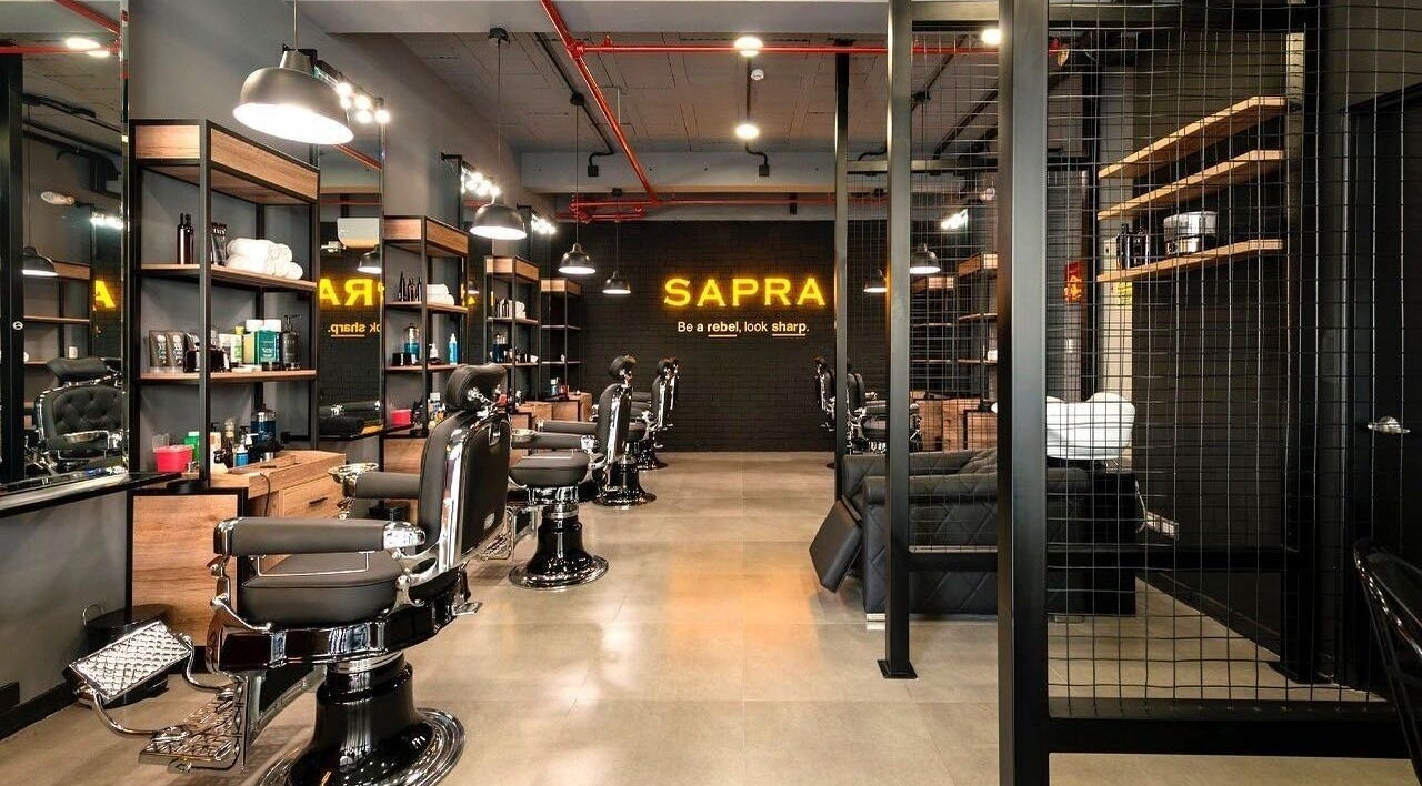 Interior moderno de Sapra Barbershop en Miraflores, Provincia De Lima, PE, mostrando sillas de barbero elegantes.