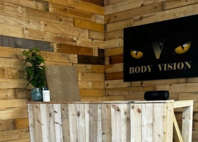 Bodyvision reception with wooden decor and a plant in Old Colwyn, Wales, GB.