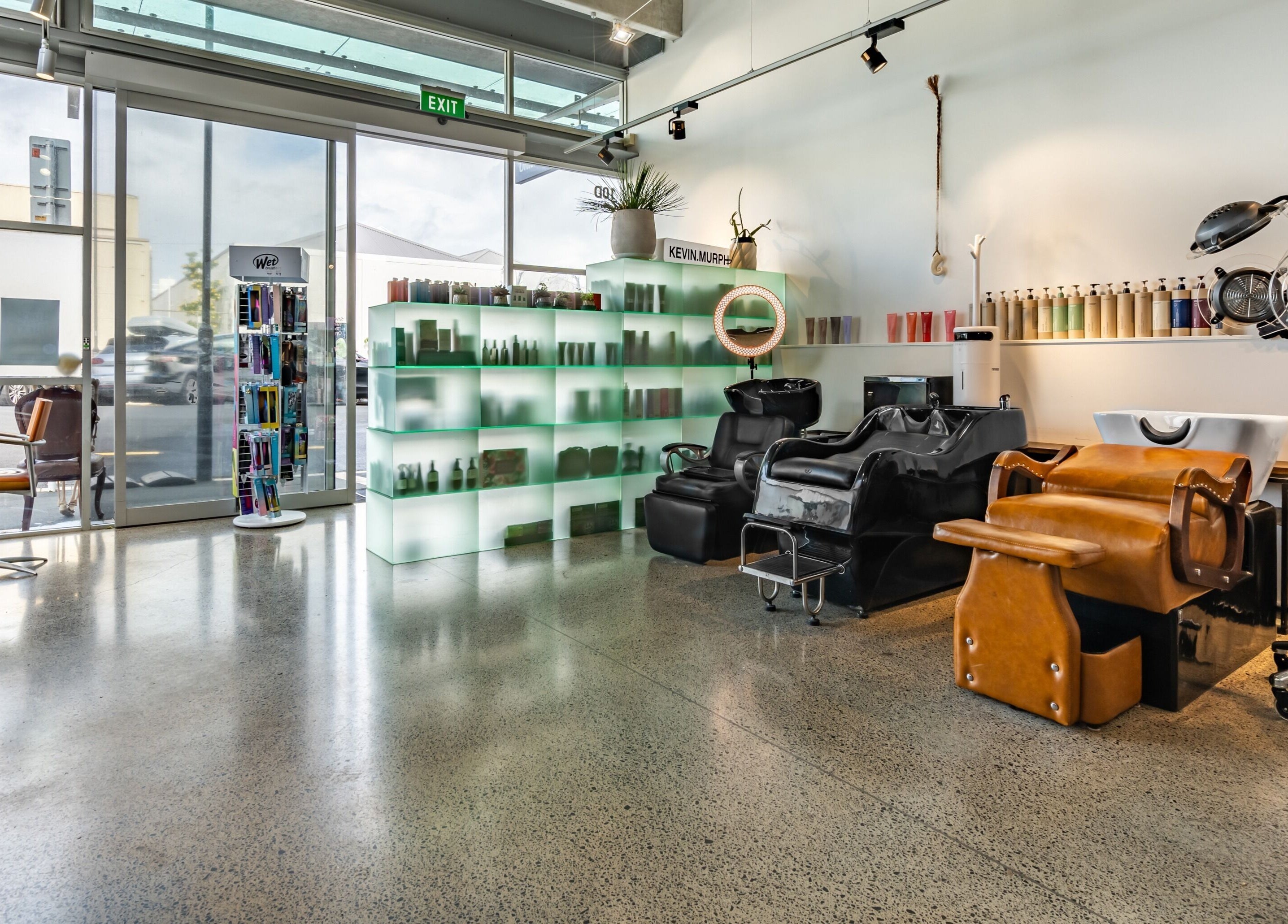 Modern salon interior at The Colour Bar, Auckland, NZ featuring sleek chairs and hair care display.