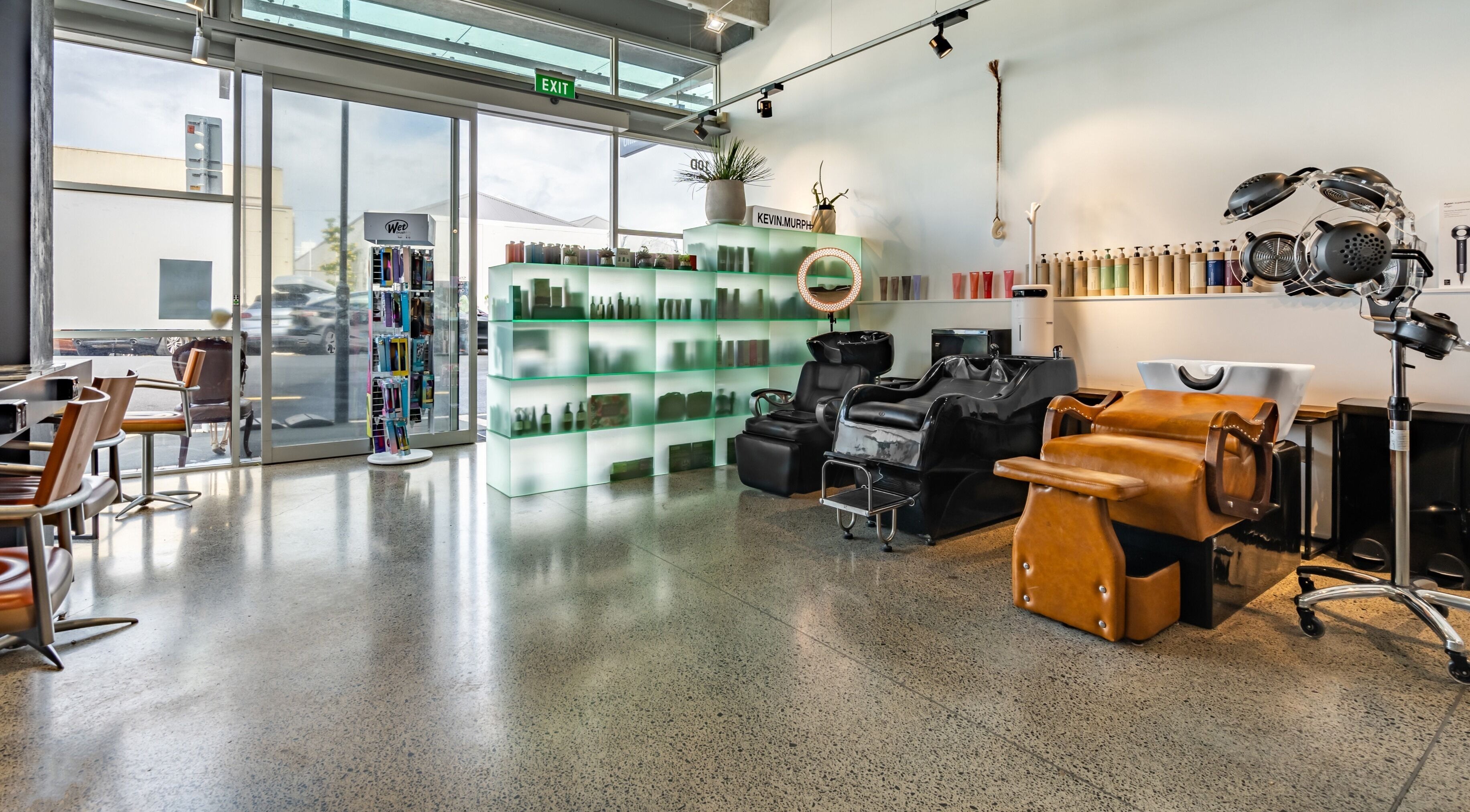 Modern salon interior at The Colour Bar, Auckland, NZ featuring sleek chairs and hair care display.