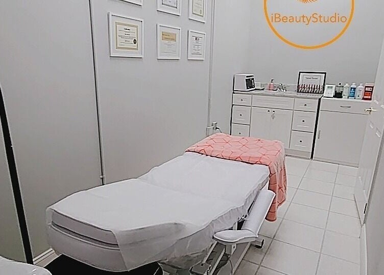 Relaxing treatment room at iBeauty Studio in Raleigh, North Carolina, US with a cozy bed and certificates displayed.