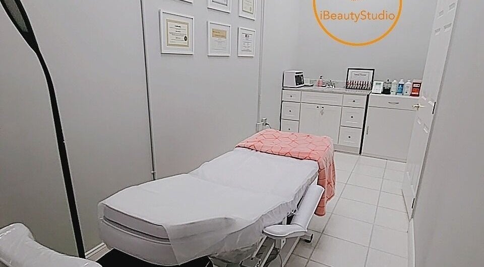 Relaxing treatment room at iBeauty Studio in Raleigh, North Carolina, US with a cozy bed and certificates displayed.