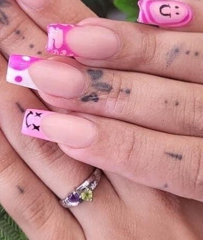 Detailed nail art on hands at The Lash Lounge, Bridgwater, England, GB, with pink and smiley face designs.
