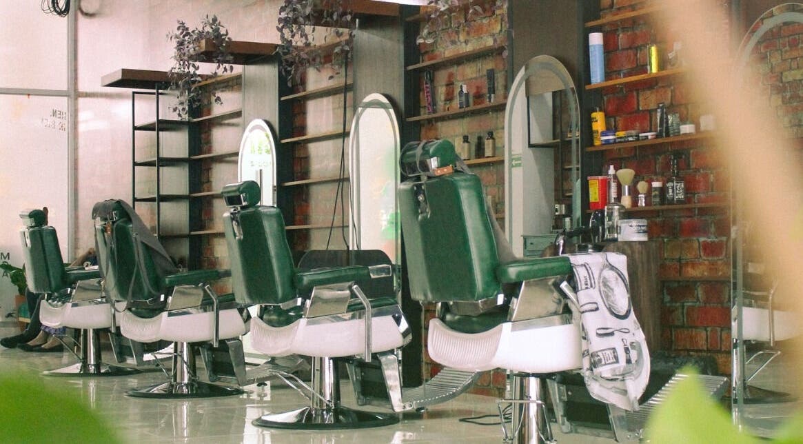 Interior moderno del Plaza Natura Garten Barberclub en Managua, NI, con sillones y espejos elegantes.