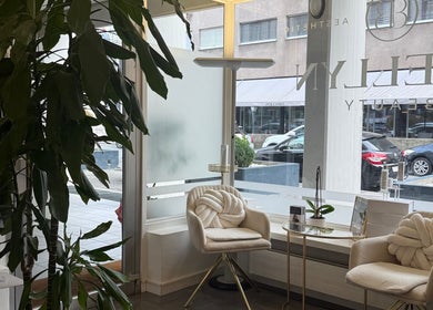 Interno elegante di Evellyn Beauty a Lugano, Ticino, CH, con sedie bianche e grandi finestre su strada.