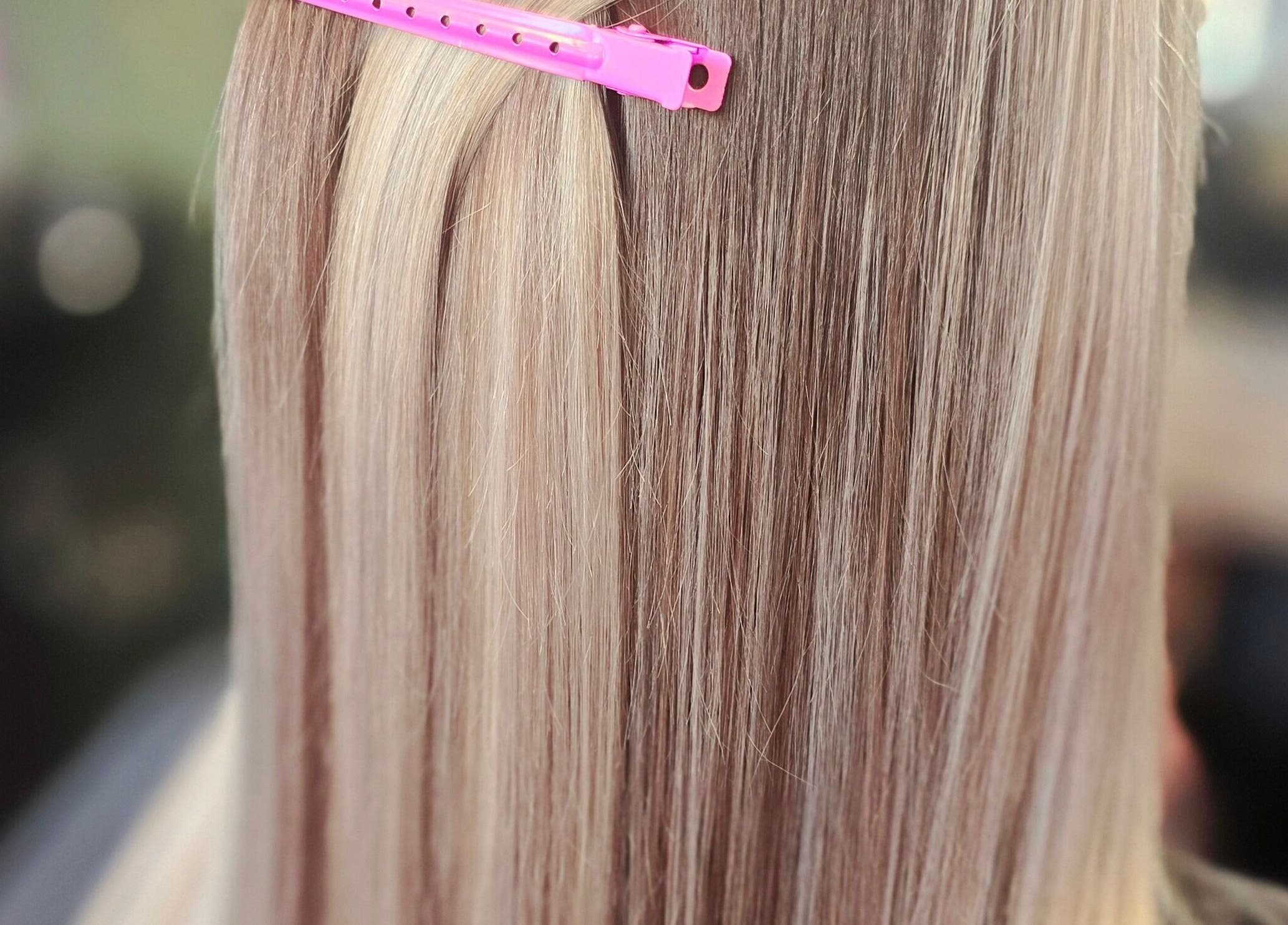 Blonde hair with pink clip at Unique Hair Design, Nelson, Nelson, NZ showcasing sleek highlights.
