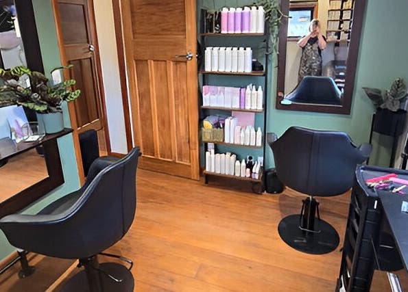 Interior of Unique Hair Design salon, Nelson, NZ, featuring stylish chairs, mirrors, and shelves with products.