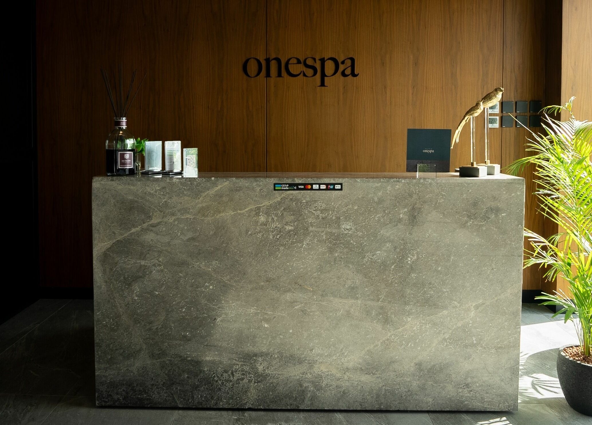 Elegant reception desk at One Spa, Riyadh, Riyadh Province, SA with modern design and lush plants.