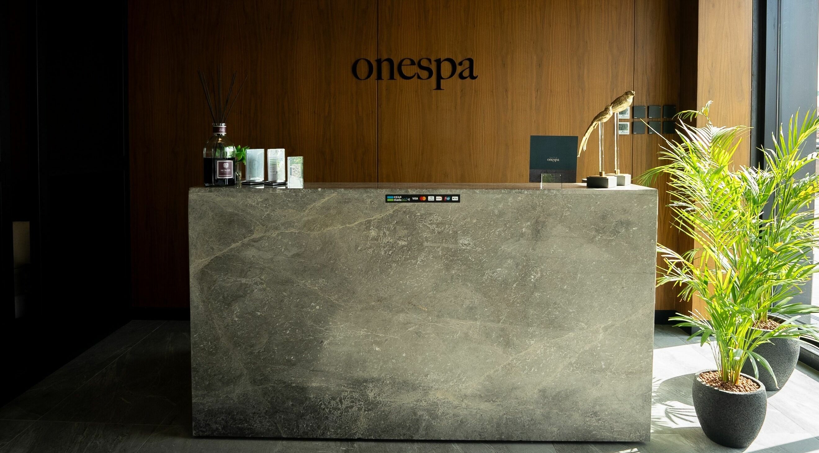 Elegant reception desk at One Spa, Riyadh, Riyadh Province, SA with modern design and lush plants.