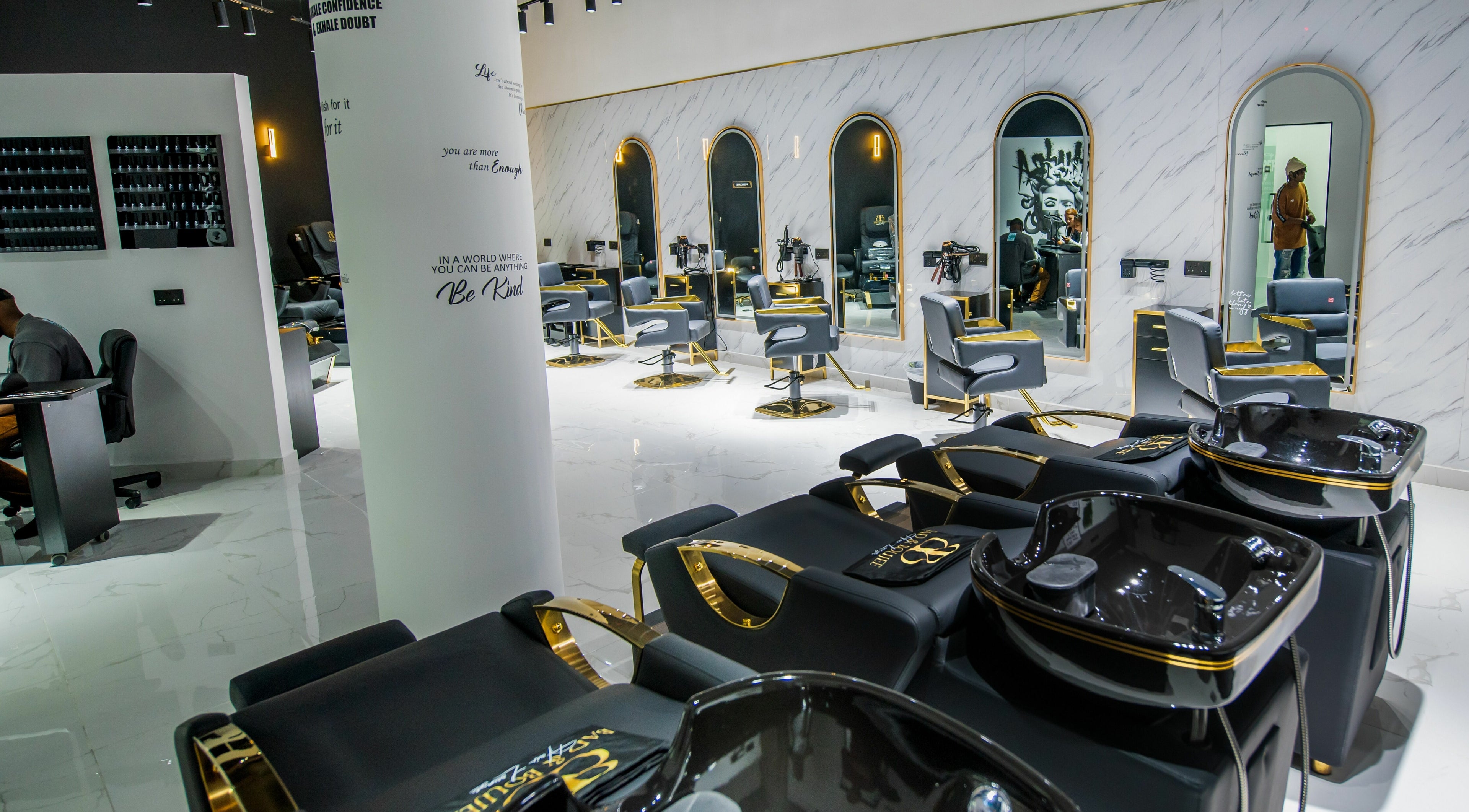 Modern salon interior at Bad & Boujee Hair Lounge, Abu Dhabi, featuring sleek black and gold styling chairs.