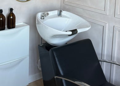 Modern shampoo station at Hairology By Rosie in Garforth, England, GB featuring a stylish black chair and white sink.