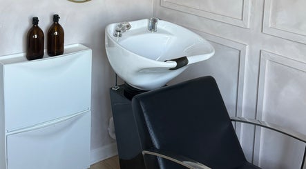 Modern shampoo station at Hairology By Rosie in Garforth, England, GB featuring a stylish black chair and white sink.