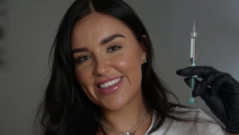 Smiling professional at LJT Aesthetics holding syringe in Herne Bay, England, GB.