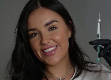 Smiling professional at LJT Aesthetics holding syringe in Herne Bay, England, GB.