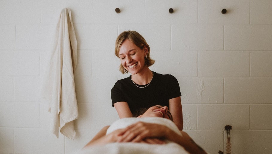 Massage therapy at Nurture in Byron Bay, New South Wales, AU. A therapist smiles while providing a calming treatment.