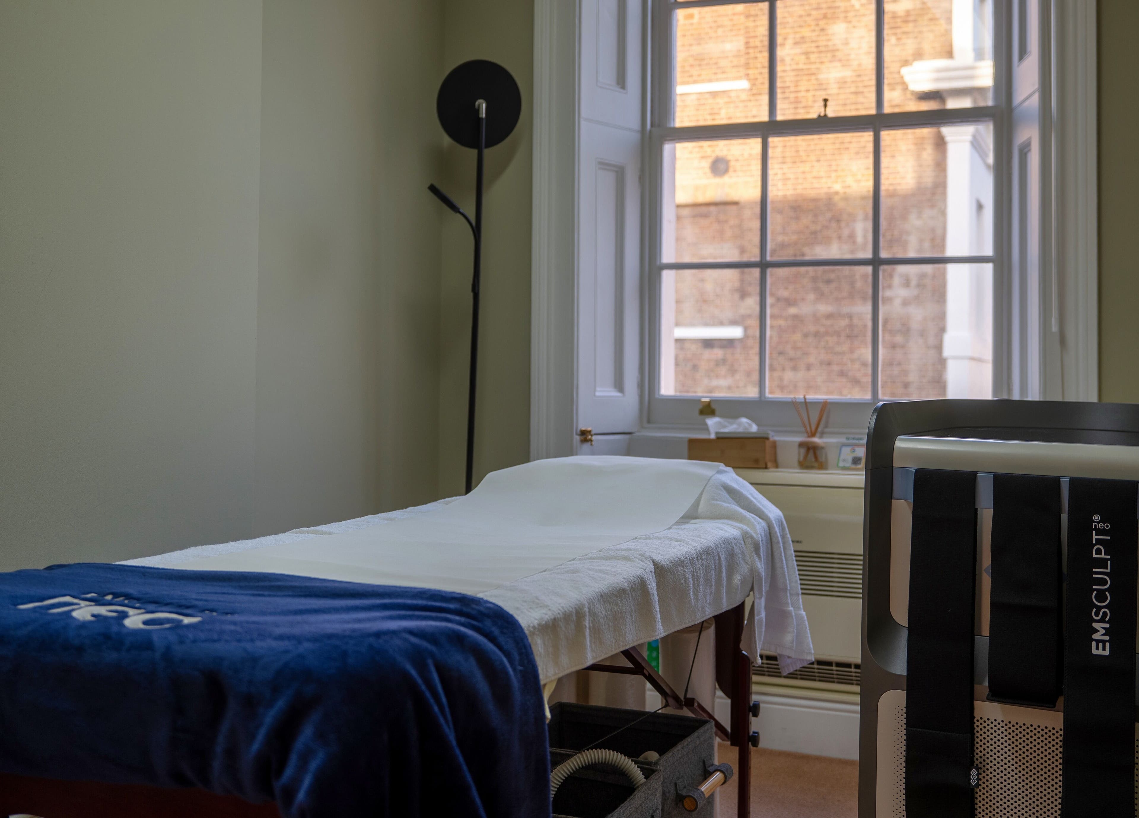 Treatment room at Reshape Clinic [Marylebone], London, England, GB with EMSculpt machine and massage bed.