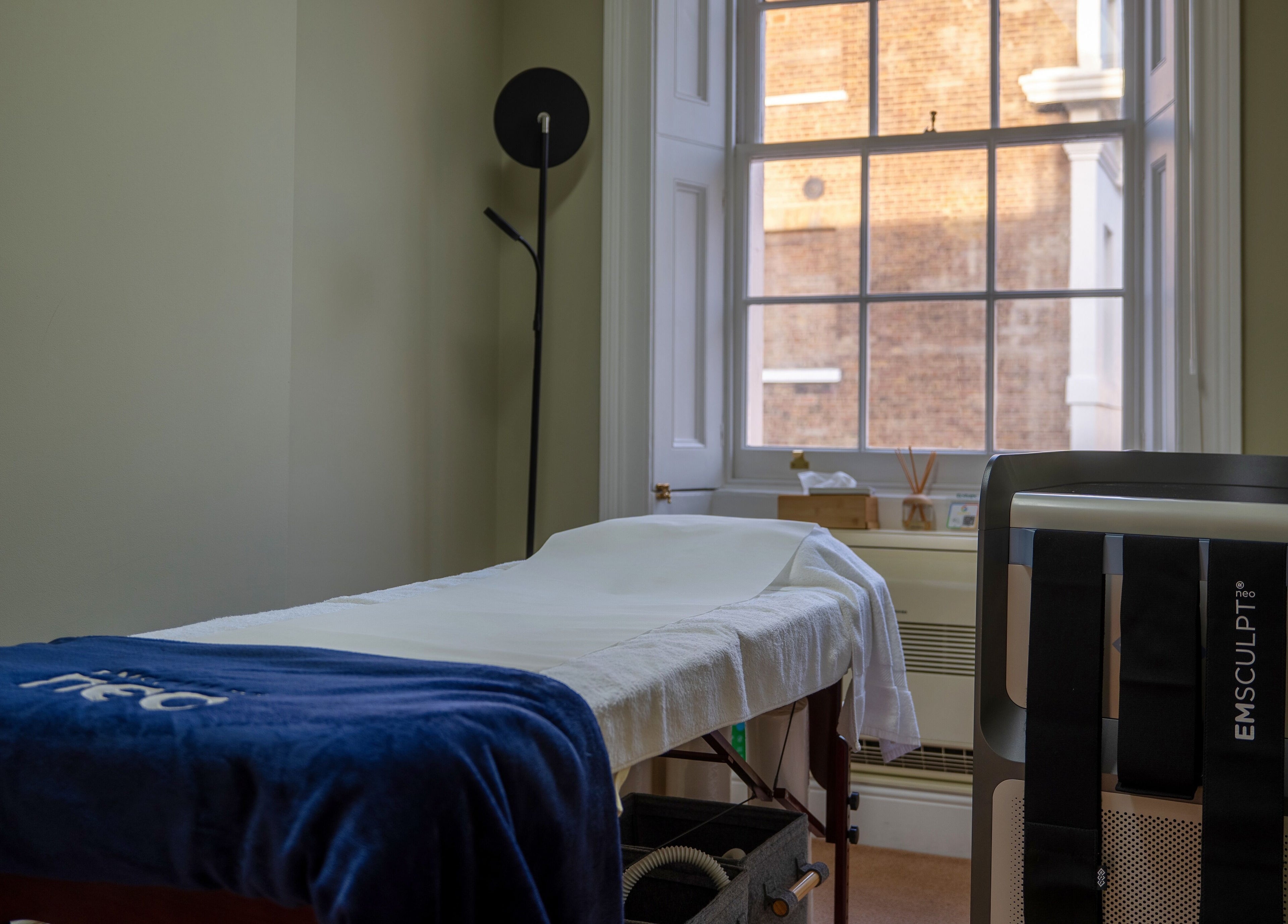 Treatment room at Reshape Clinic [Marylebone], London, England, GB with EMSculpt machine and massage bed.