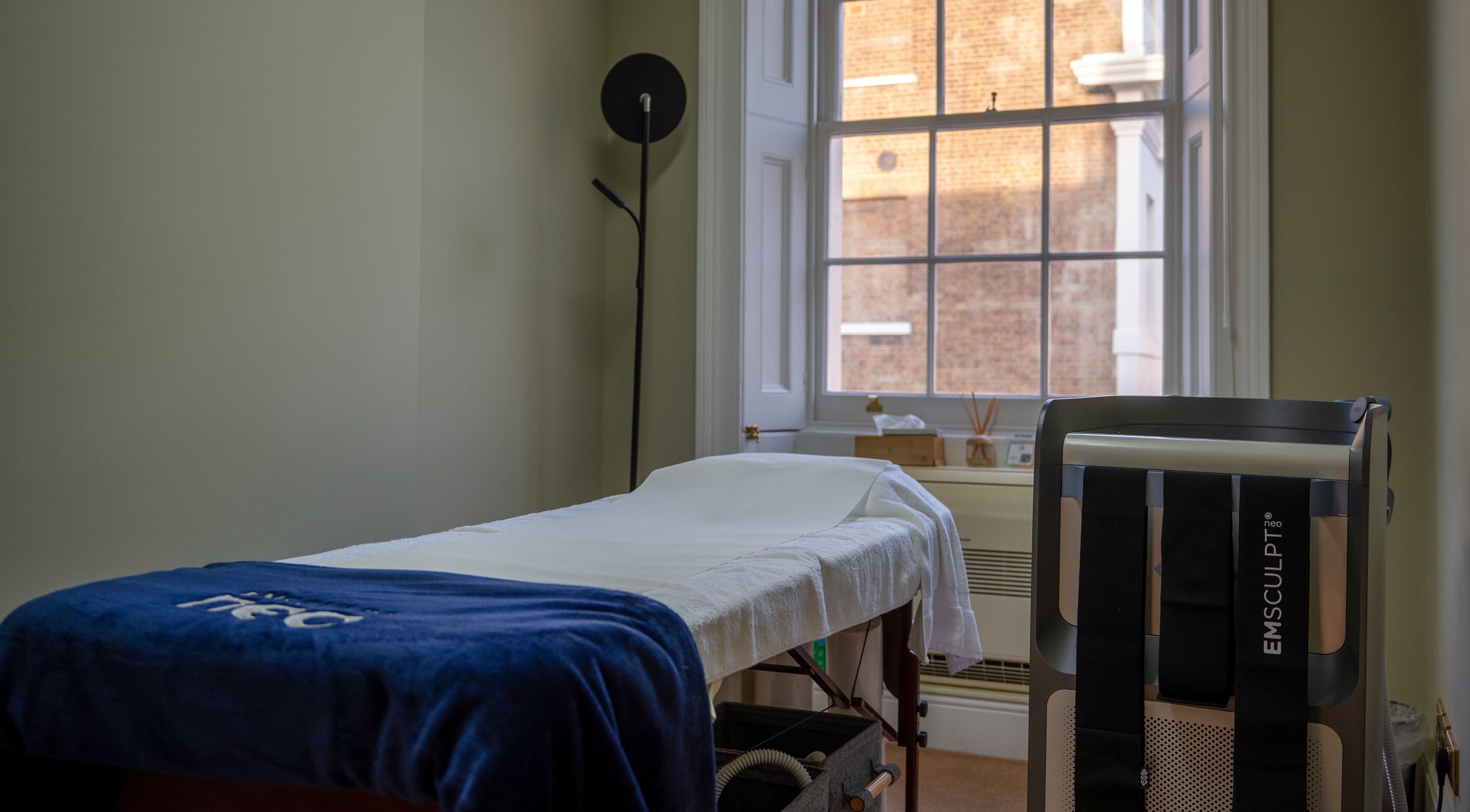 Treatment room at Reshape Clinic [Marylebone], London, England, GB with EMSculpt machine and massage bed.
