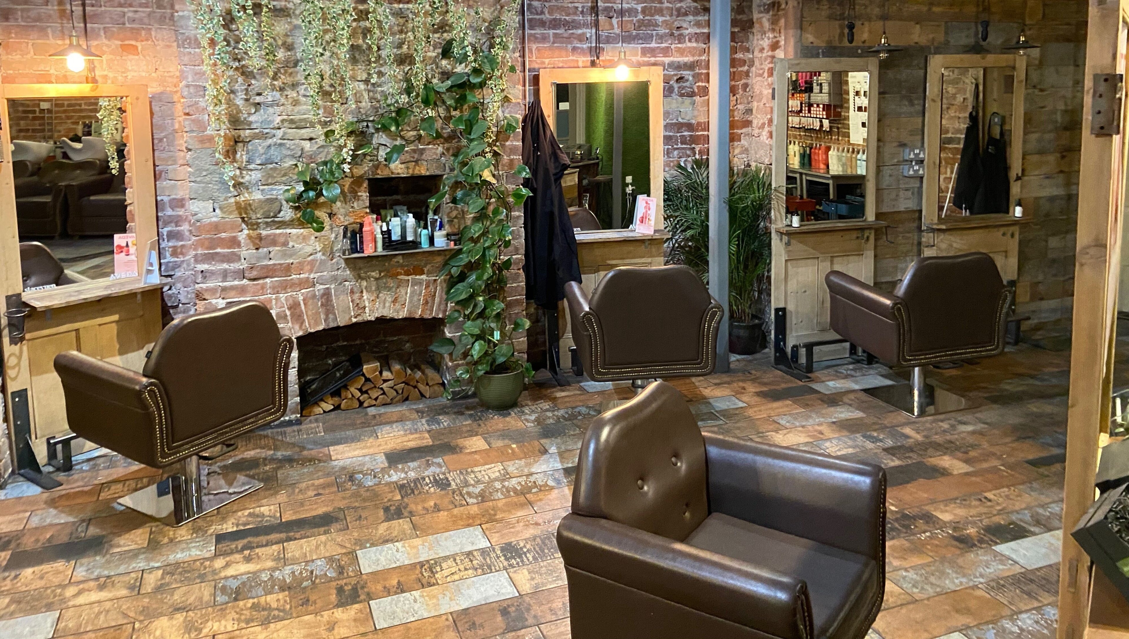 Cozy interior of Stacey Yuen Aveda Brynmill in Brynmill, Wales, GB with vintage salon chairs and brick design.