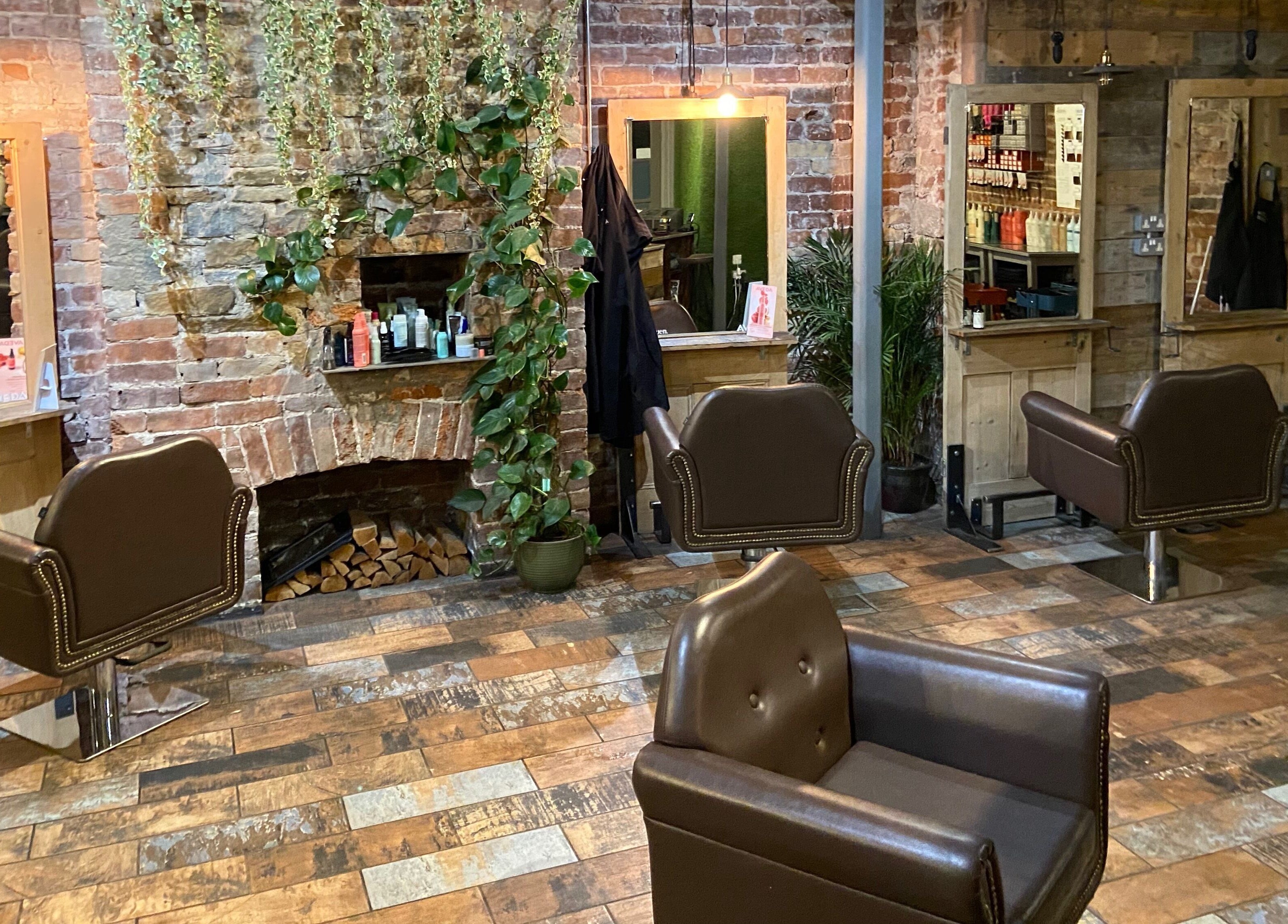 Cozy interior of Stacey Yuen Aveda Brynmill in Brynmill, Wales, GB with vintage salon chairs and brick design.