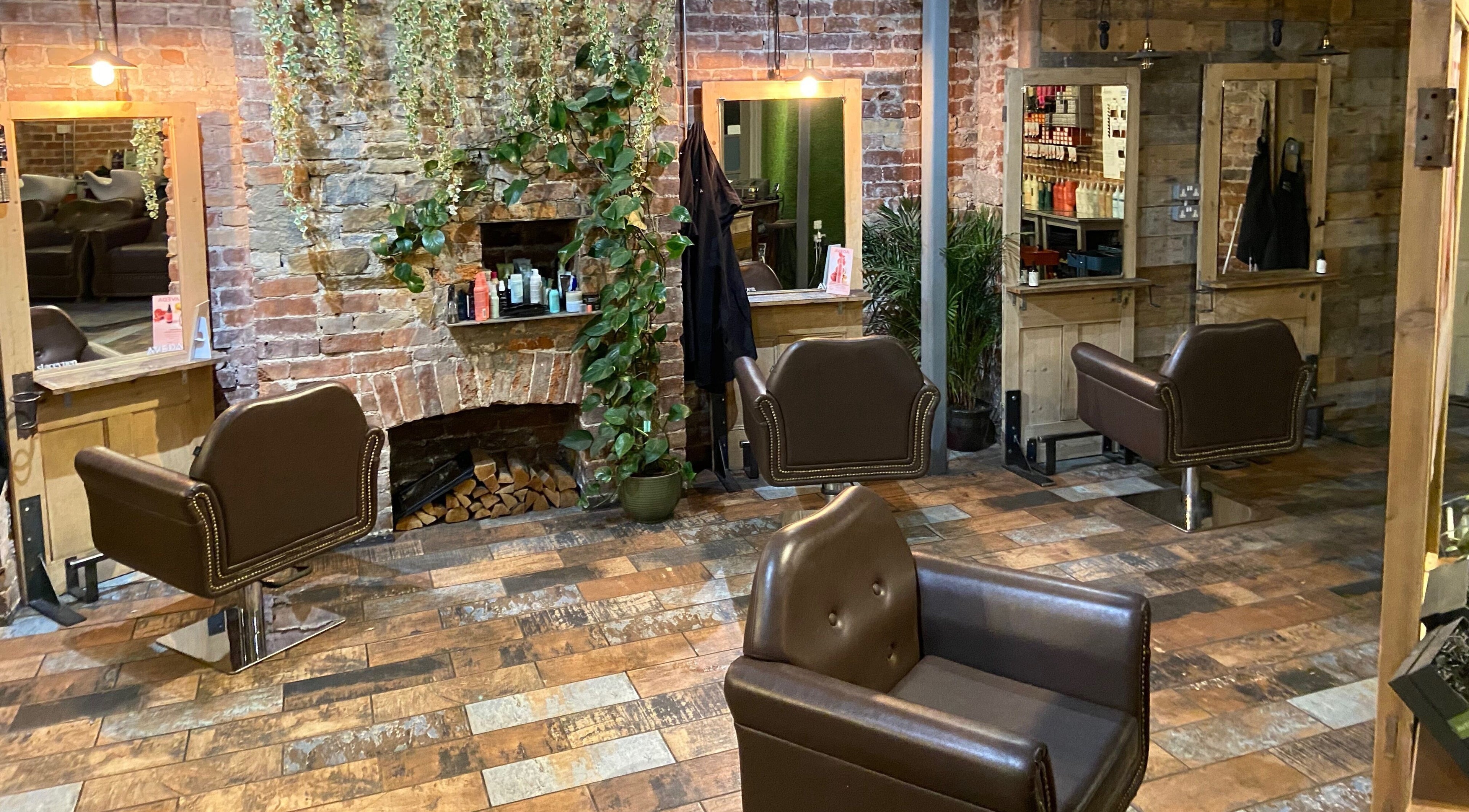 Cozy interior of Stacey Yuen Aveda Brynmill in Brynmill, Wales, GB with vintage salon chairs and brick design.