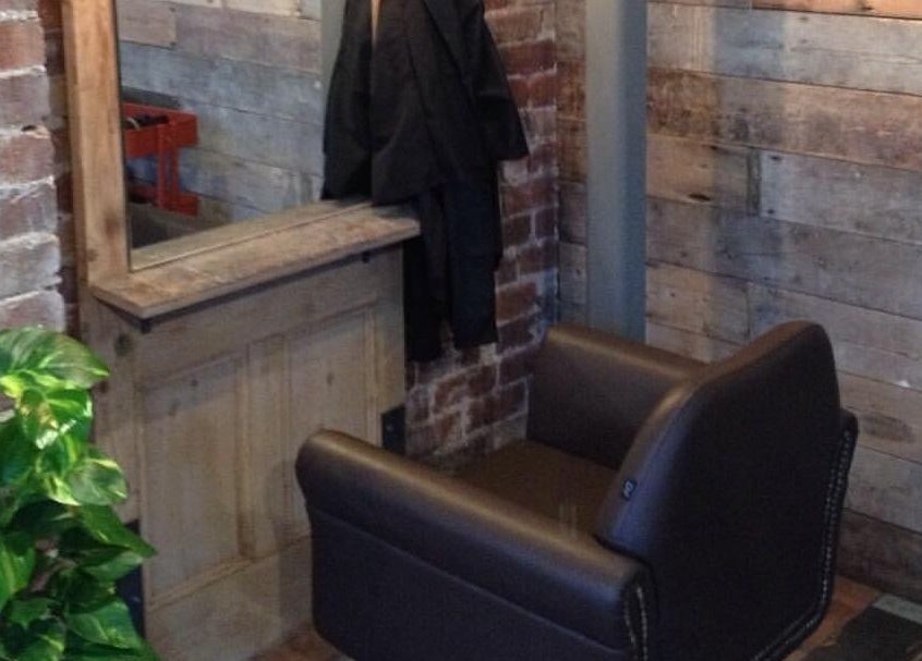 A cozy salon chair in Stacey Yuen Aveda Brynmill, Brynmill, Wales, GB, with rustic wooden decor.