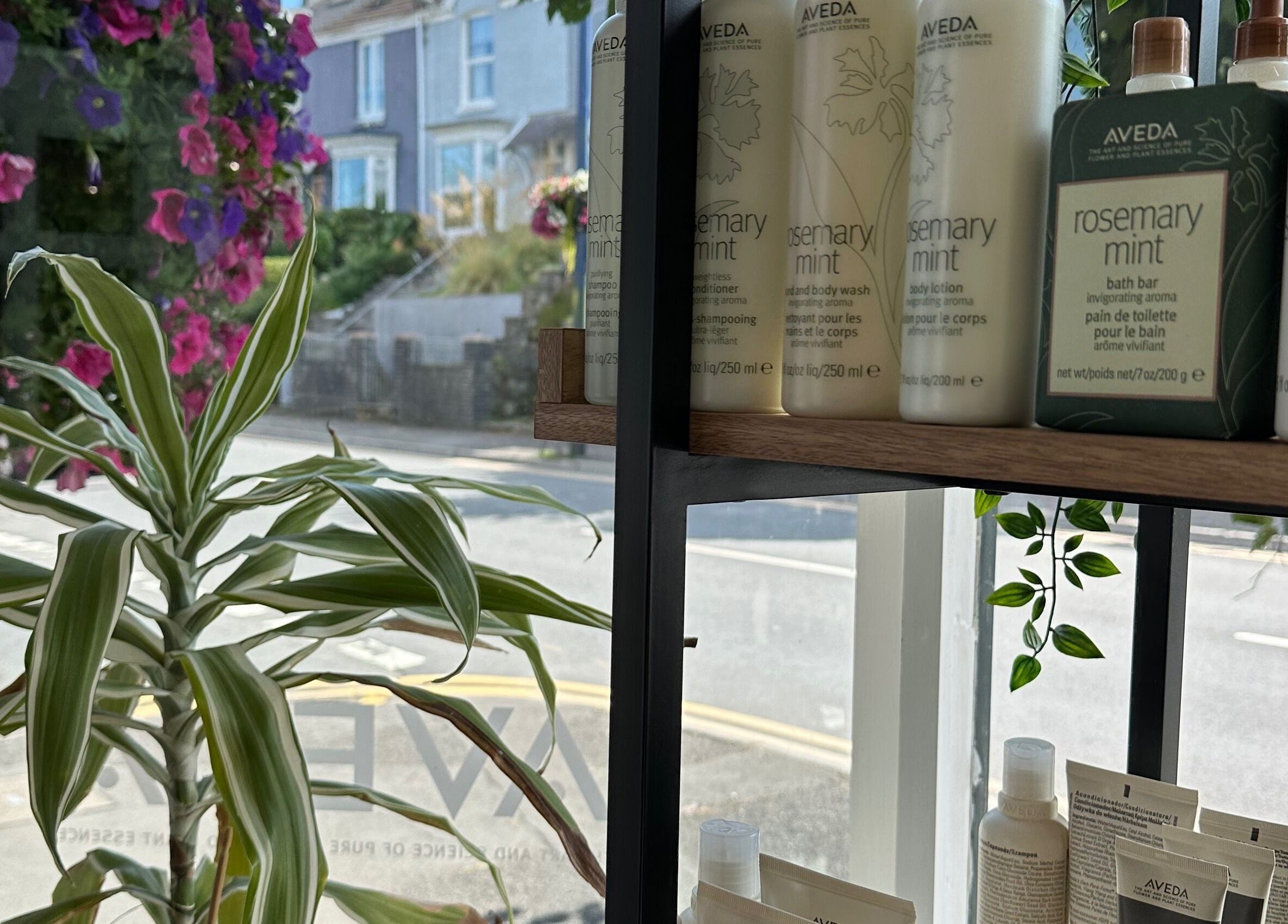 Aveda products displayed at Stacey Yuen Aveda Mumbles, Swansea, Wales, GB, with vibrant outdoor view.