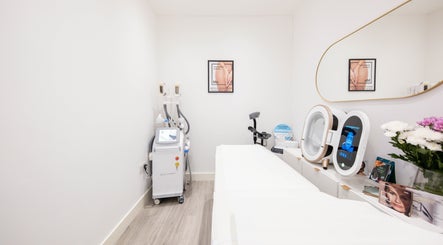 Sleek treatment room in Oxa Beauty, London, England, GB with advanced beauty equipment and fresh flowers.
