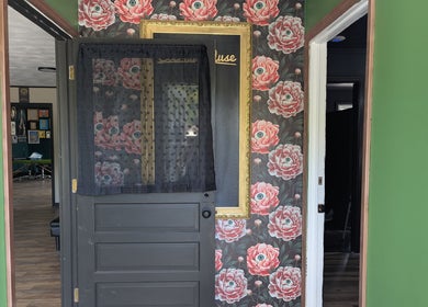 Entrance of Eternal Muse Tattoo & Piercing in Vestal, New York with floral wallpaper and decor.