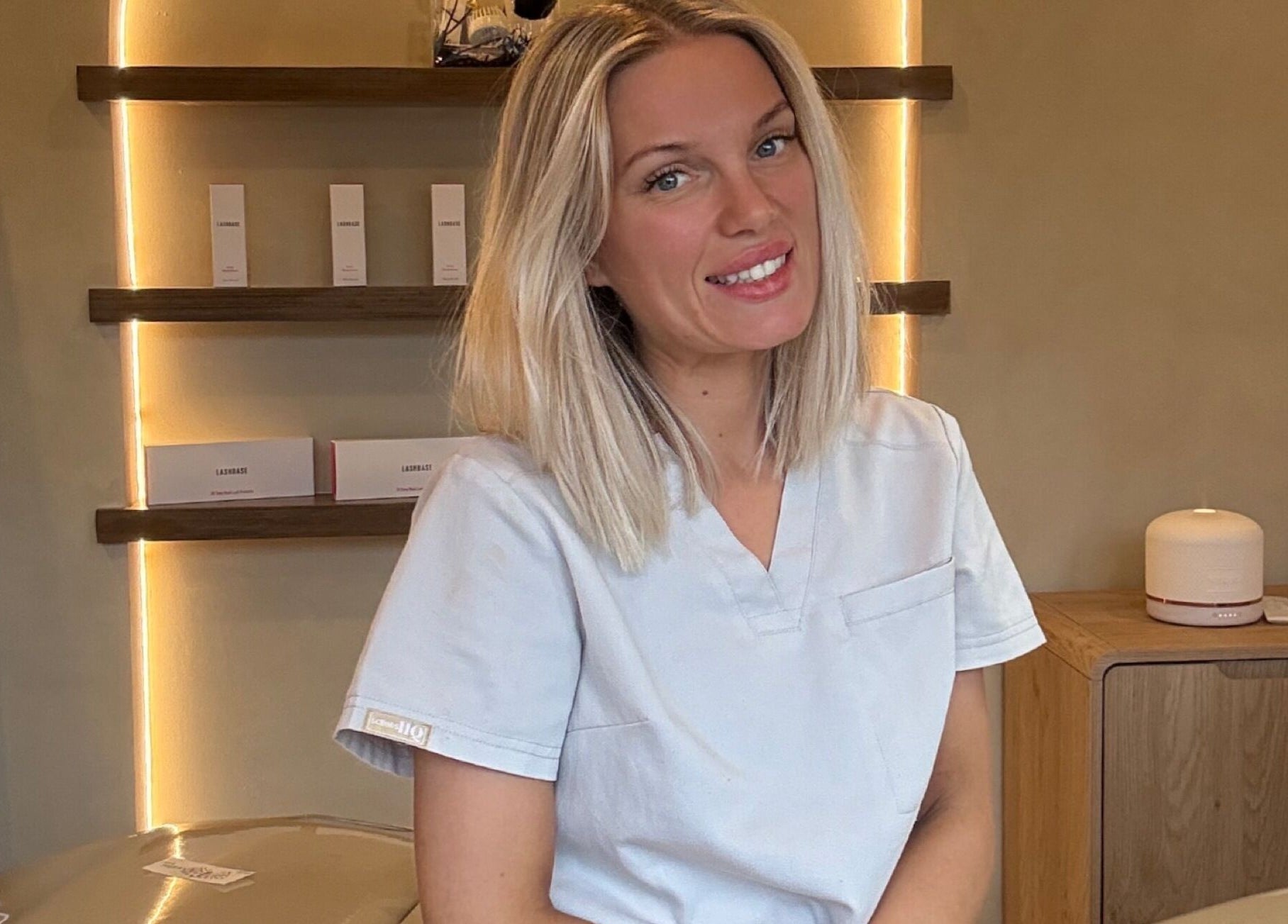 Glow By Clo therapist in Aldershot, England, GB ambient room with lit shelves and beauty products.