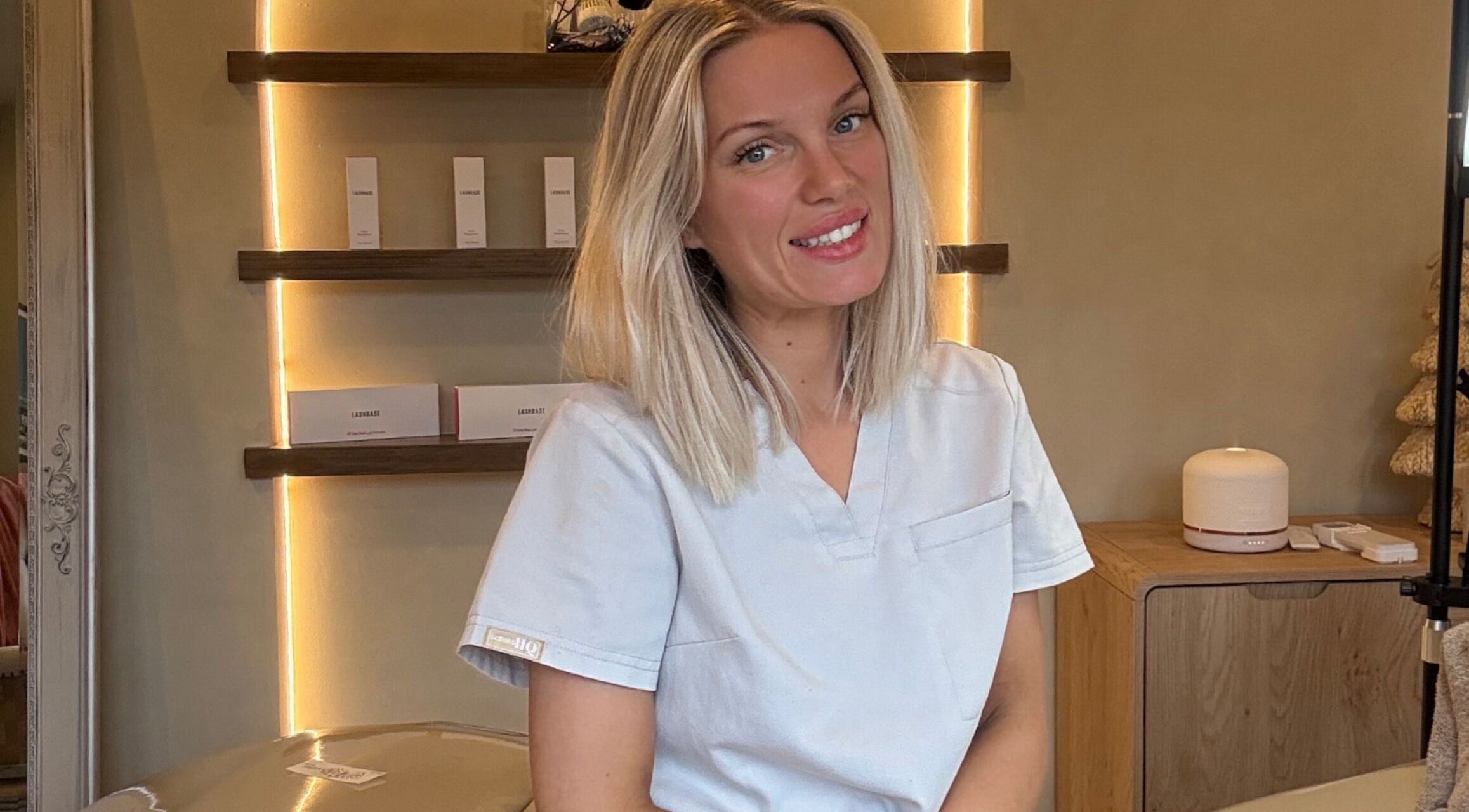 Glow By Clo therapist in Aldershot, England, GB ambient room with lit shelves and beauty products.