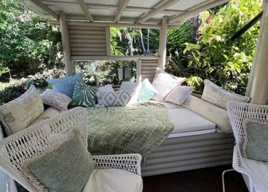 Outdoor relaxation lounge at Essenc8 Relaxation Massage in Cawarral, Queensland, AU, with cozy pillows and greenery.