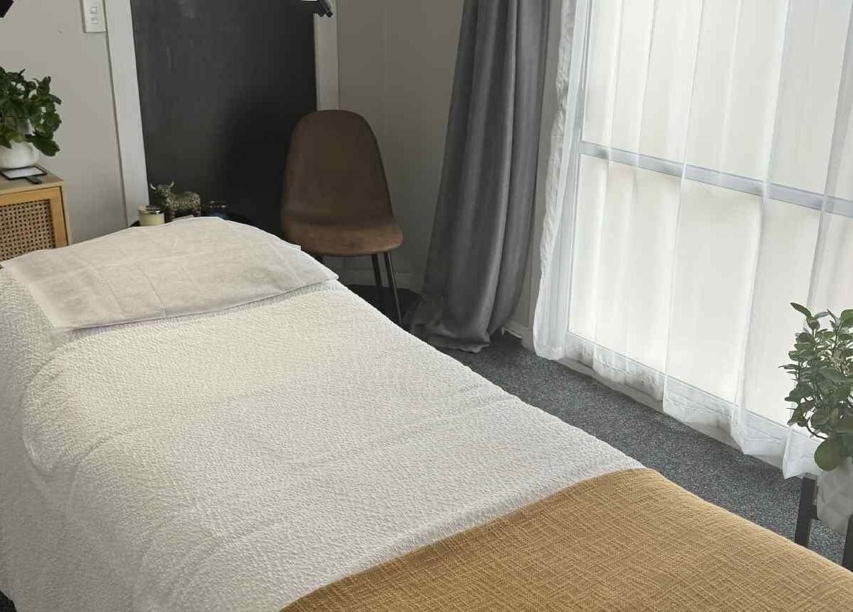 Tranquil treatment room at Haven Beauty, Taupō, Waikato, NZ, featuring a cozy bed and lush plants by window.