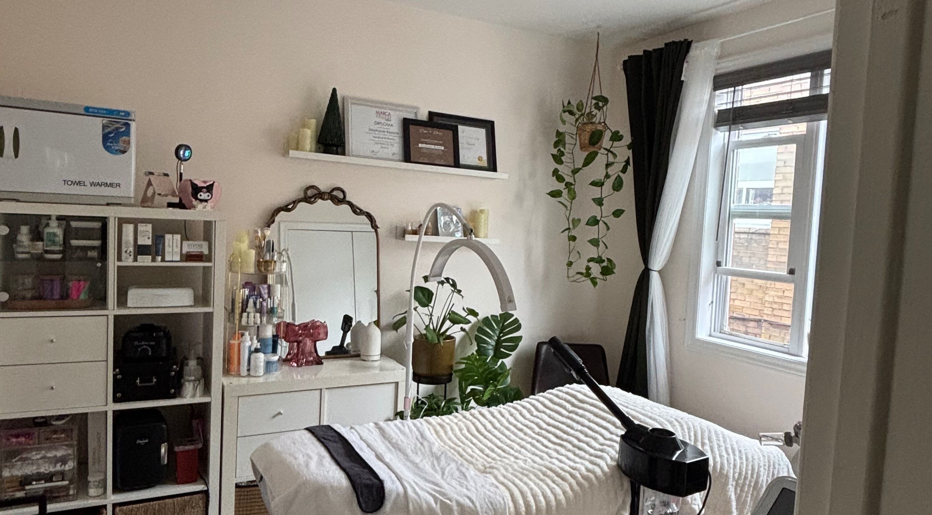 Stephyskin treatment room in Toronto, Ontario, CA with cozy decor and a massage table near a bright window.