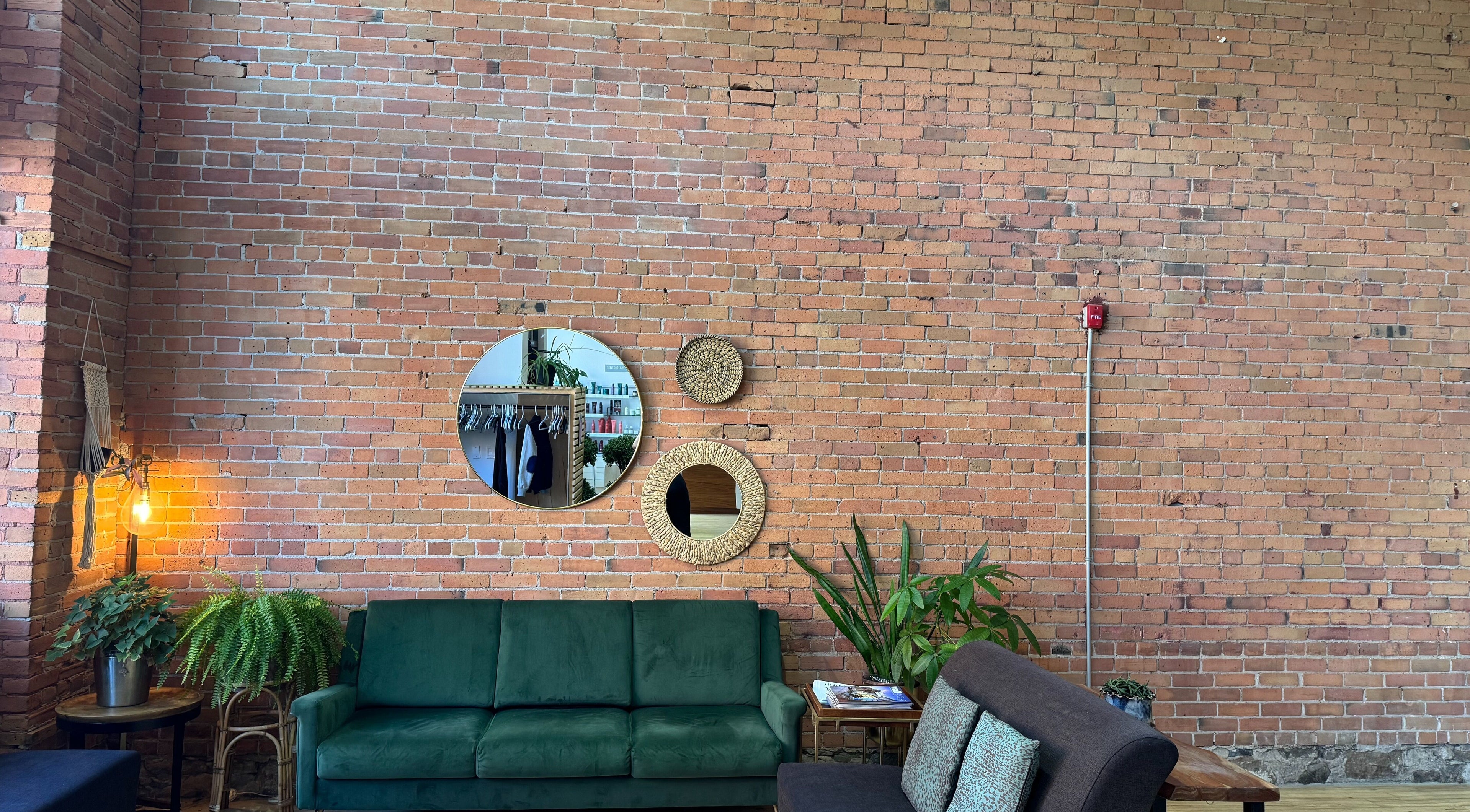 Stylish lounge at evoke salon + spa, Thunder Bay, Ontario, CA, featuring a green sofa and decorative mirrors.
