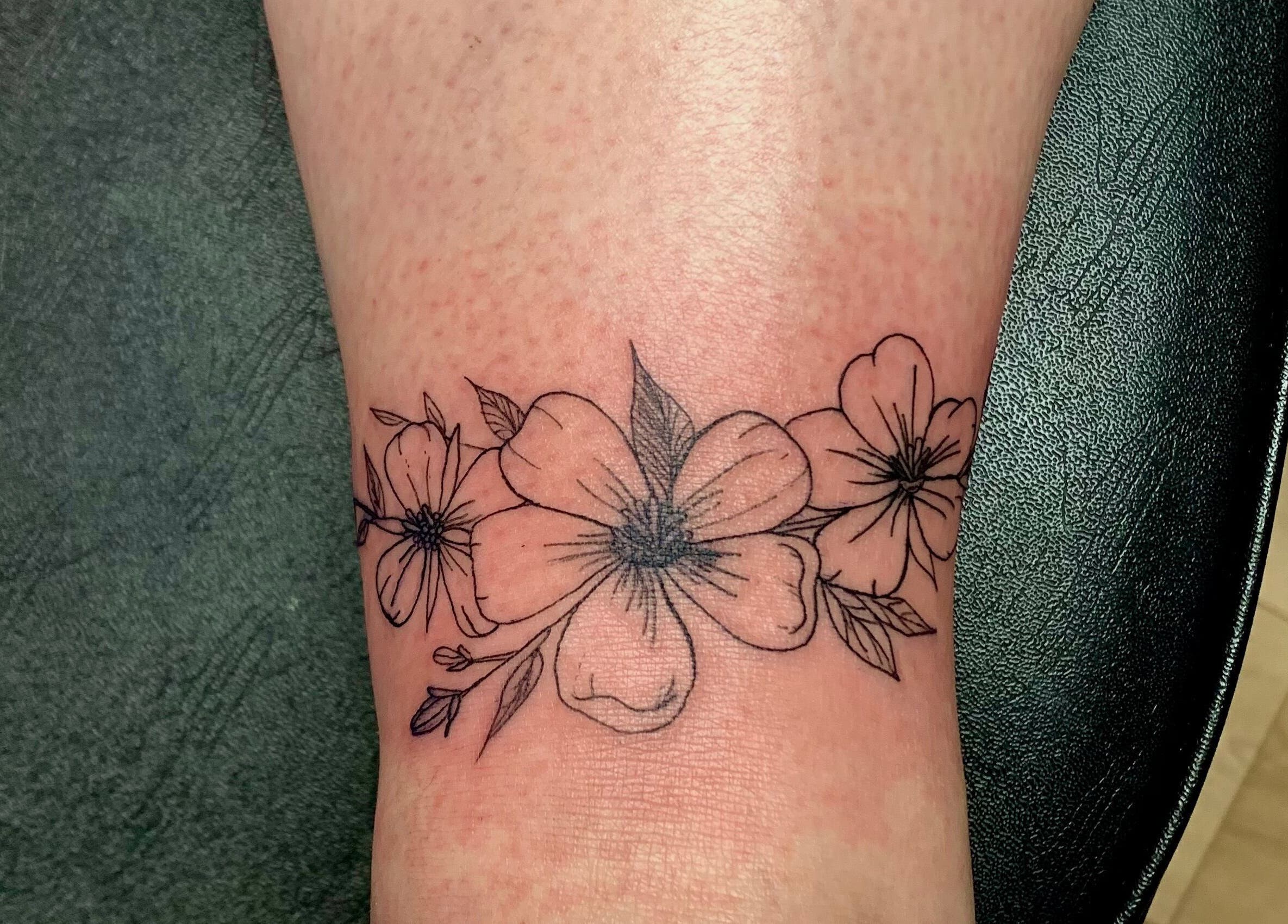 Intricate floral ankle tattoo at Ebb and Flow Studio IL, Peru, Illinois, US. Delicate blossom design showcasing studio's artistry.
