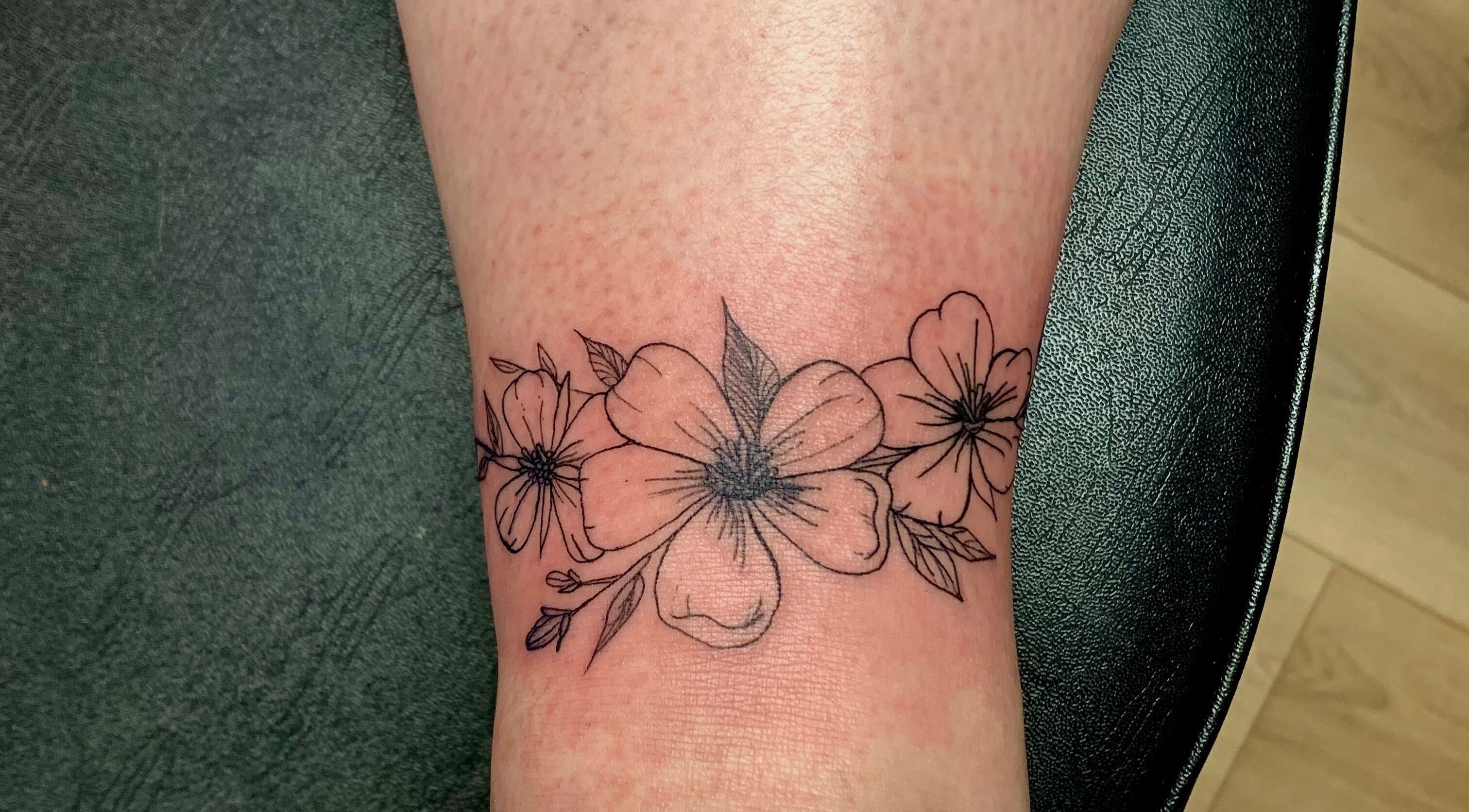Intricate floral ankle tattoo at Ebb and Flow Studio IL, Peru, Illinois, US. Delicate blossom design showcasing studio's artistry.