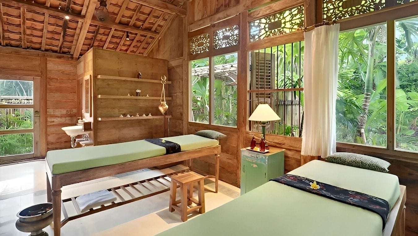 Relaxing spa room at 1919 Spa, Bali, Bali, ID with wooden interior and massage tables overlooking lush greenery.