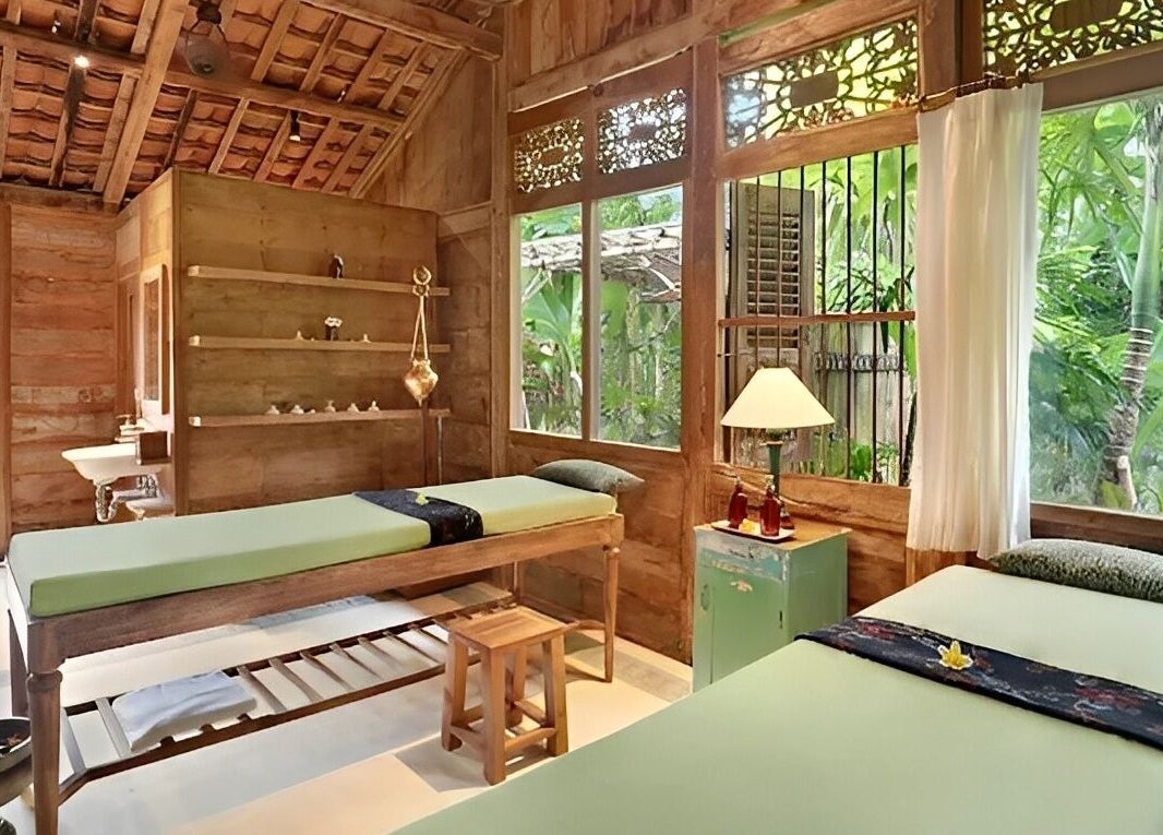 Relaxing spa room at 1919 Spa, Bali, Bali, ID with wooden interior and massage tables overlooking lush greenery.