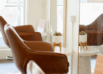 Stylish seating area at Aveta Hair and Body, Port Noarlunga, SA, AU with brown leather chairs and decor.