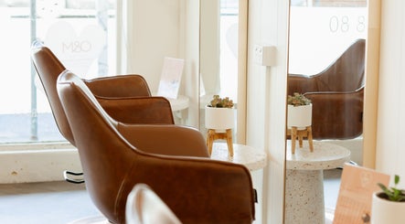 Stylish seating area at Aveta Hair and Body, Port Noarlunga, SA, AU with brown leather chairs and decor.
