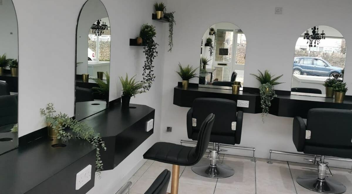 Modern salon interior at Hair Of Thrones in Frome, England, GB featuring stylish chairs and greenery.