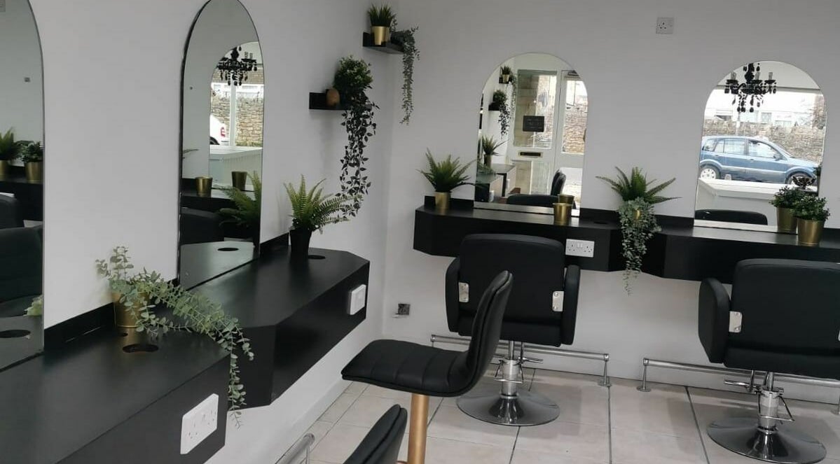 Modern salon interior at Hair Of Thrones in Frome, England, GB featuring stylish chairs and greenery.
