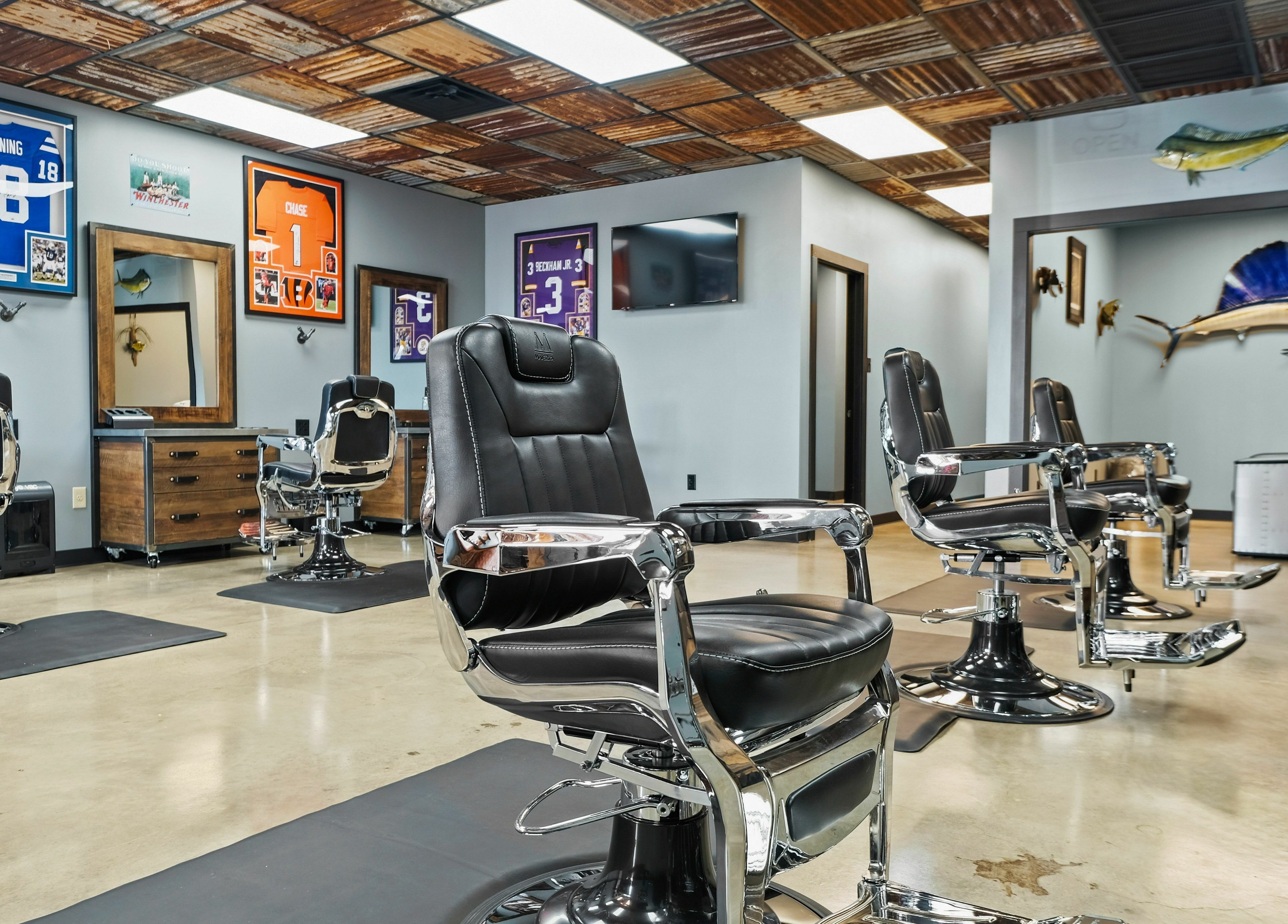 Chic barbershop interior at Mancave Cenla in Pineville, Louisiana, US with sleek chairs and sports decor.