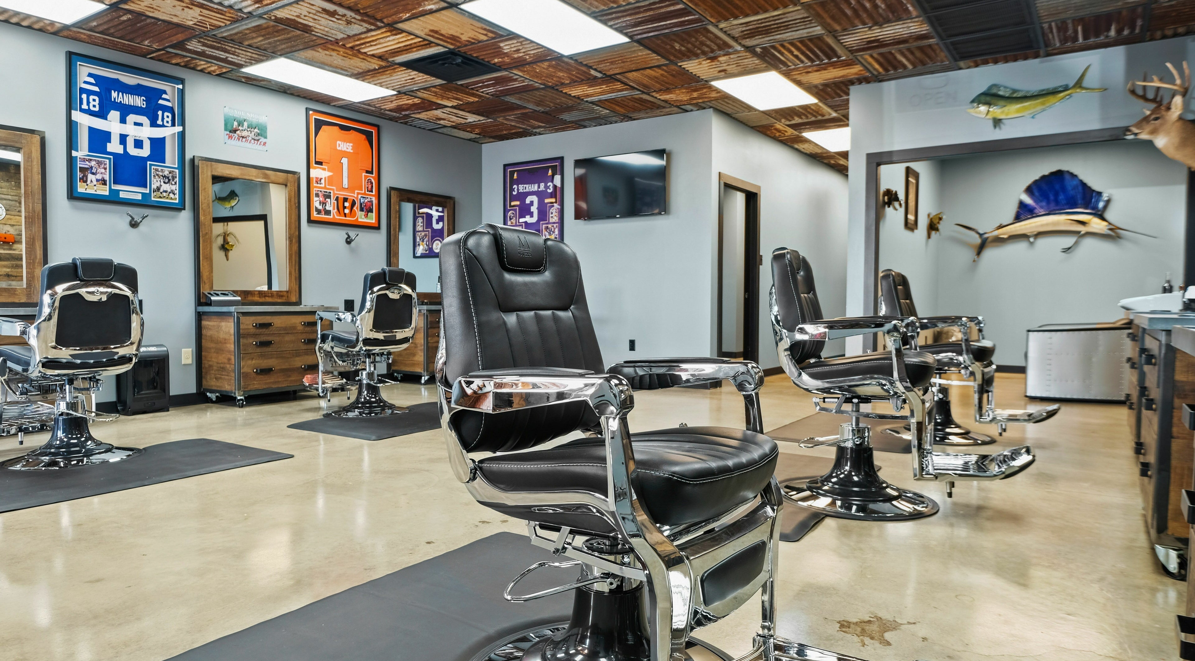 Chic barbershop interior at Mancave Cenla in Pineville, Louisiana, US with sleek chairs and sports decor.