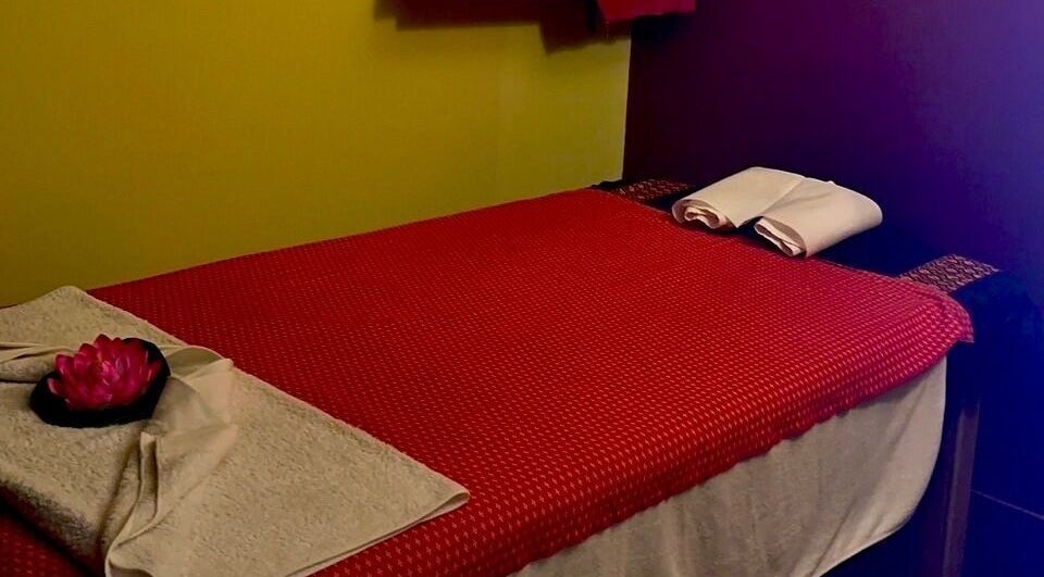 Massage table at Nakhon Thai Massage in Auckland, Auckland, NZ, with red cover and folded towels.