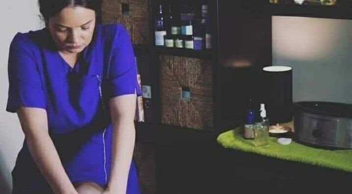 Therapist at Enlighten Therapy in Arnold, England, GB performing a calming massage in a serene setting.
