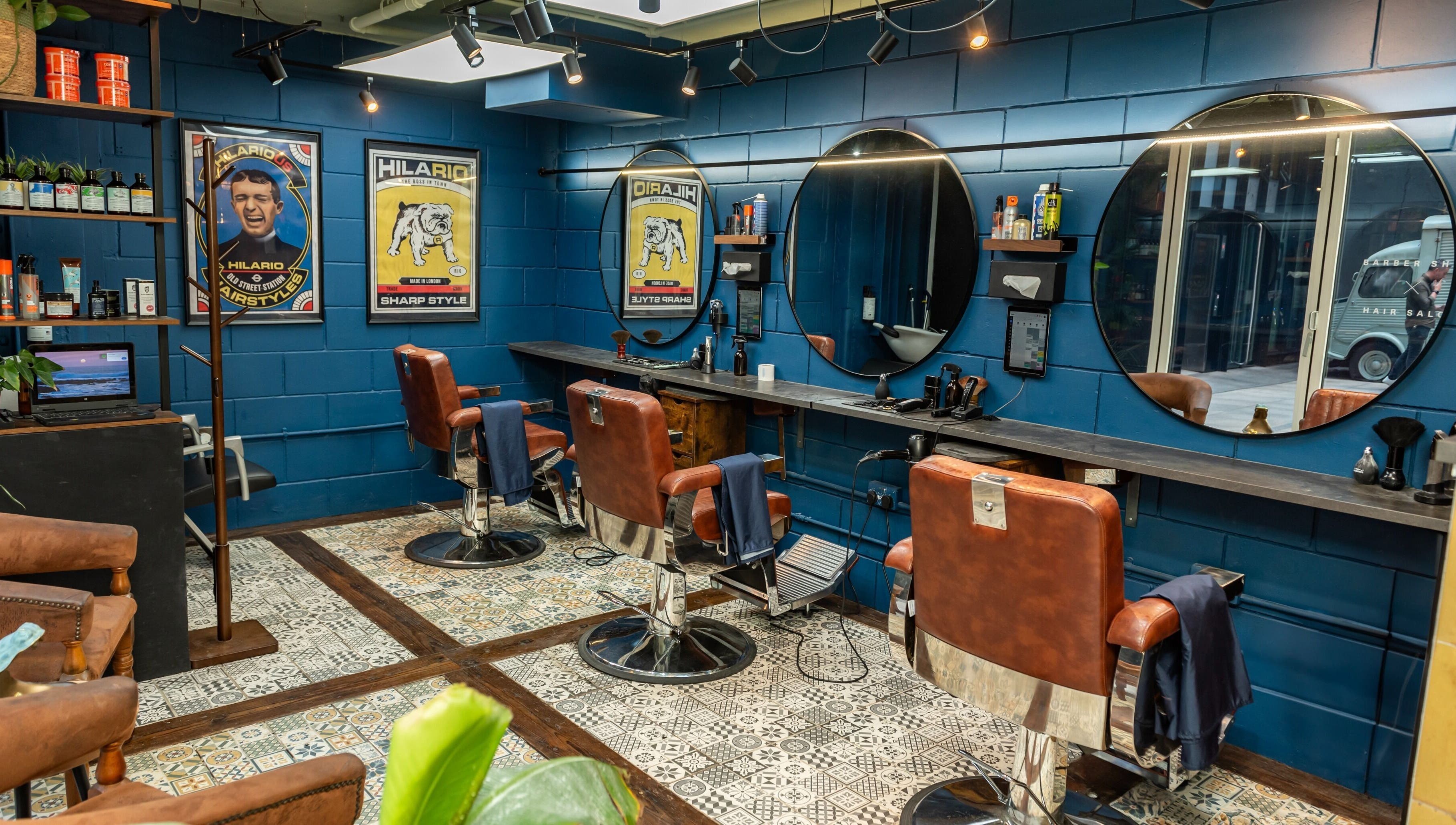 Vintage-style barber chairs at Hilario, London, England, GB, with blue walls and circular mirrors, creating a stylish ambiance.