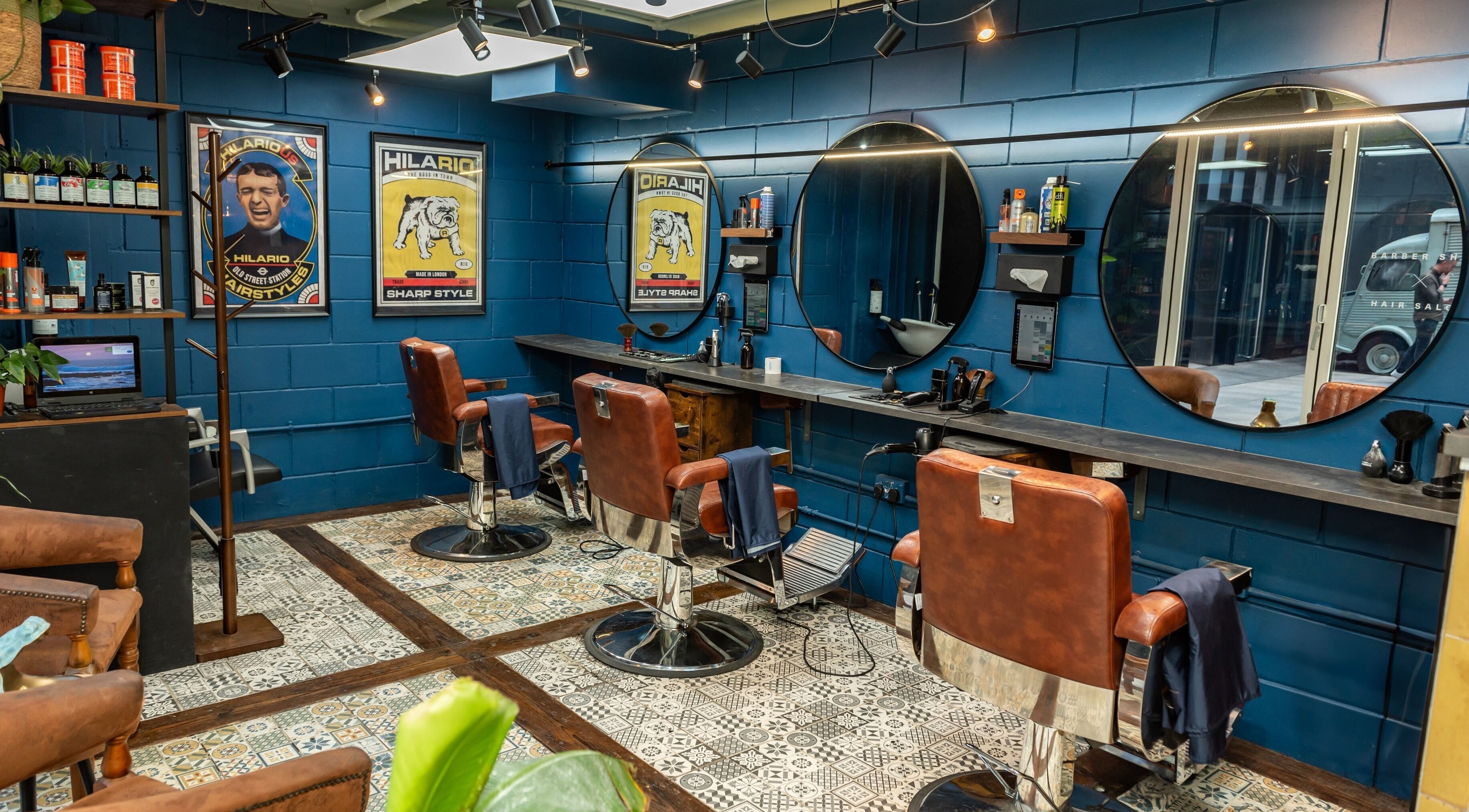 Vintage-style barber chairs at Hilario, London, England, GB, with blue walls and circular mirrors, creating a stylish ambiance.